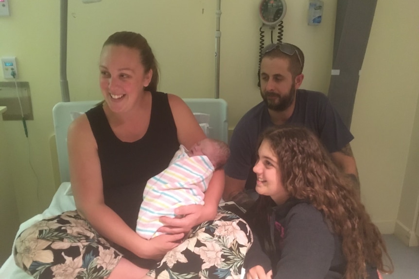 A happy mother with a new-born baby, grown daughter and husband.
