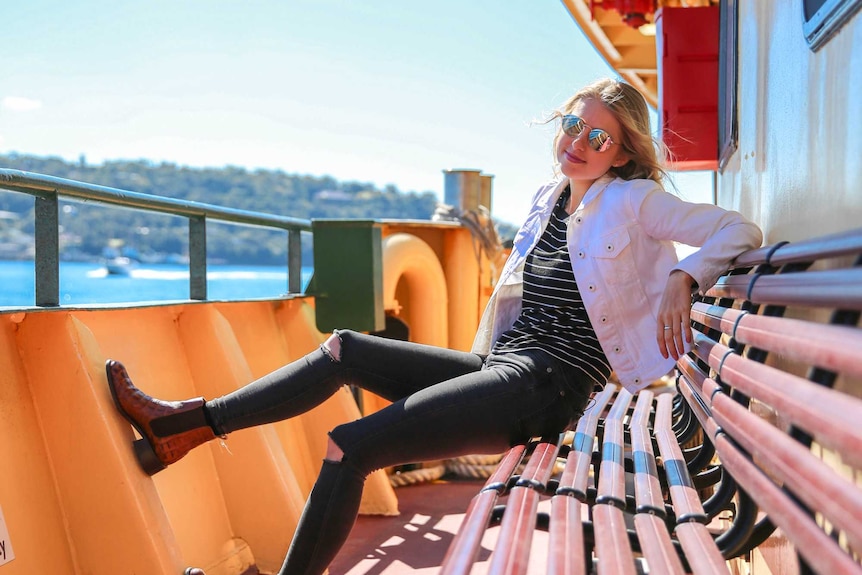 Amy Lyons sits on a bench on a Sydney Harbour ferry