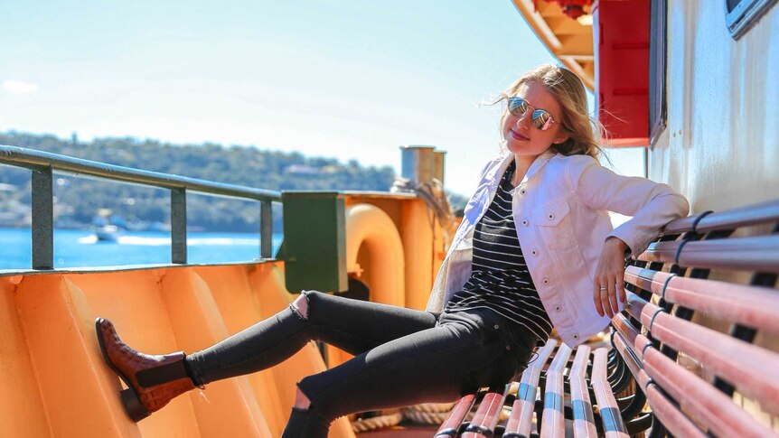 Amy Lyons sits on a bench on a Sydney Harbour ferry