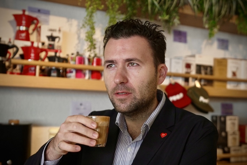 A man holds a coffee cup at a cafe.