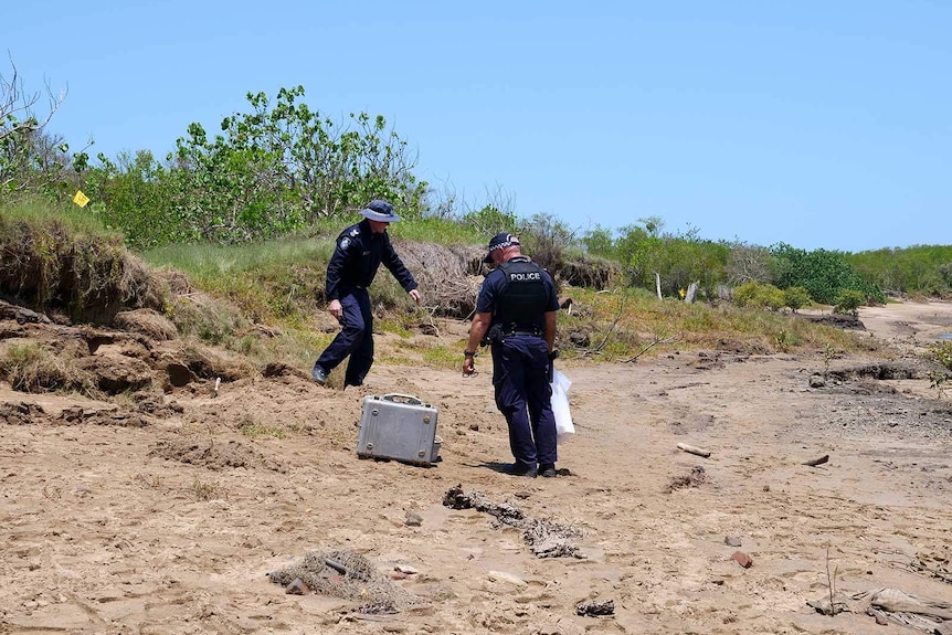 Police officers examining a riverbank near the water's edge
