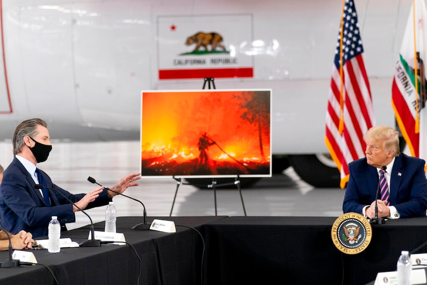 Californian Governor Gavin Newsome, wearing a mask, gestures at US President Donald Trump, who is not wearing a mask.