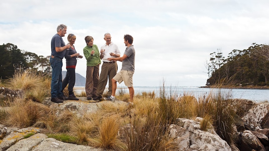 Tour guide Rob Knight standing on the remote Bruny Island coast line with tourists.