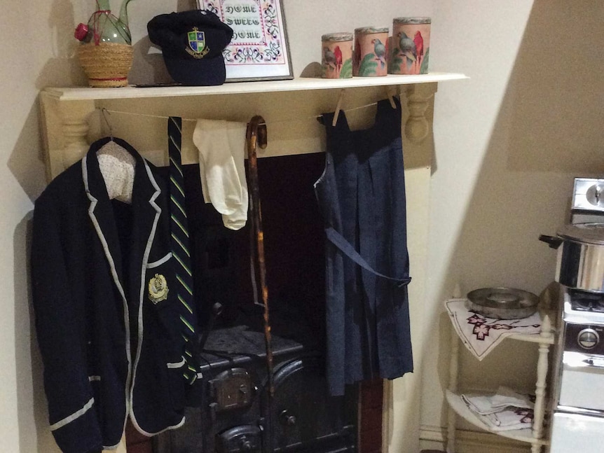 School uniforms hanging by a fireplace.