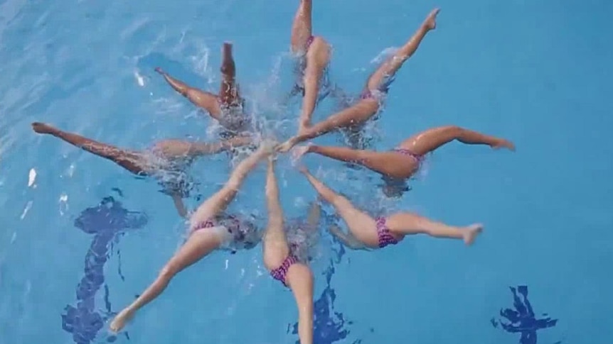 A team of eight artistic swimmers in sync