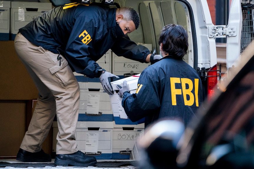Federal agents load a vehicle with evidence boxes.