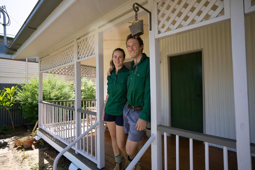 Woman and man in green shirts standing in front of house