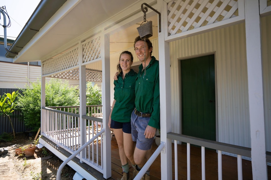 Woman and man in green shirts standing in front of house