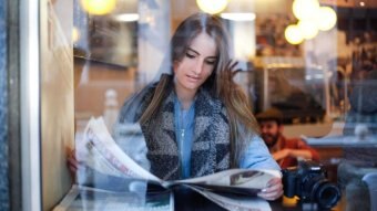 A woman reads the news paper in a coffee shop.