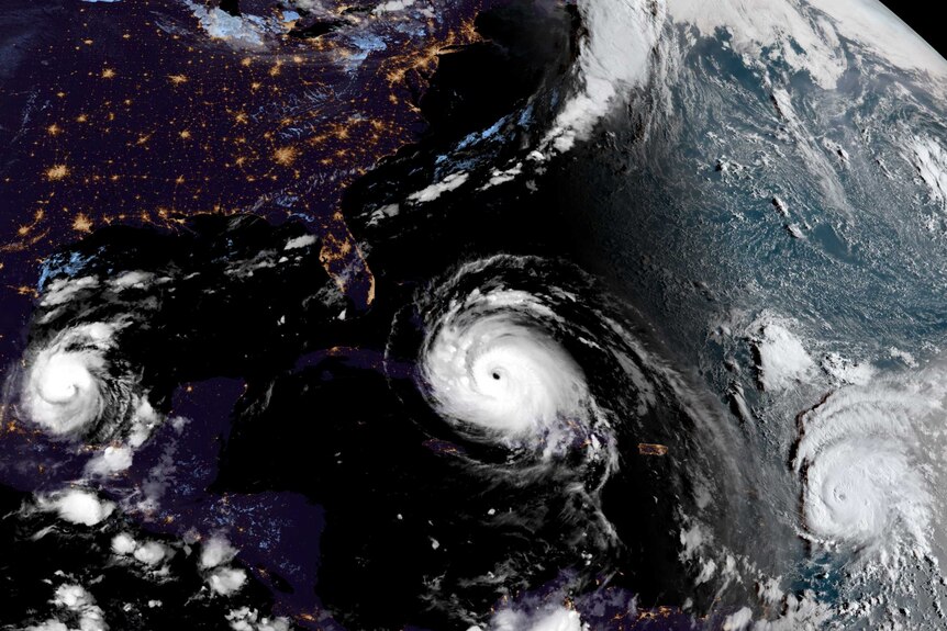 A satellite map of the world shows three major hurricanes.