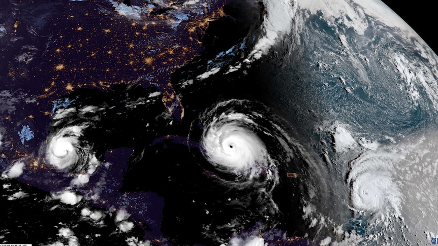 A satellite map of the world shows three major hurricanes.
