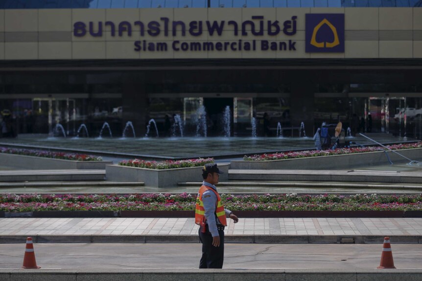 A security guard walks past Siam Commercial Bank