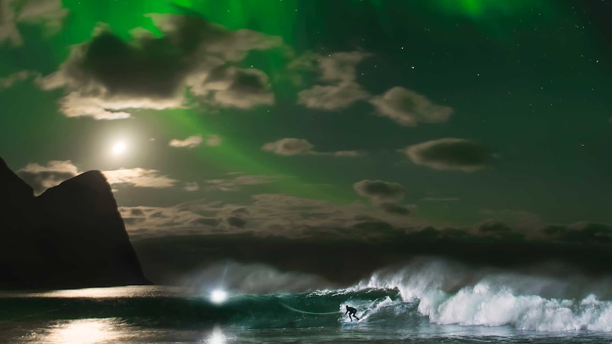 Mick Fanning surfs a wave under the Northern Lights in Norway.