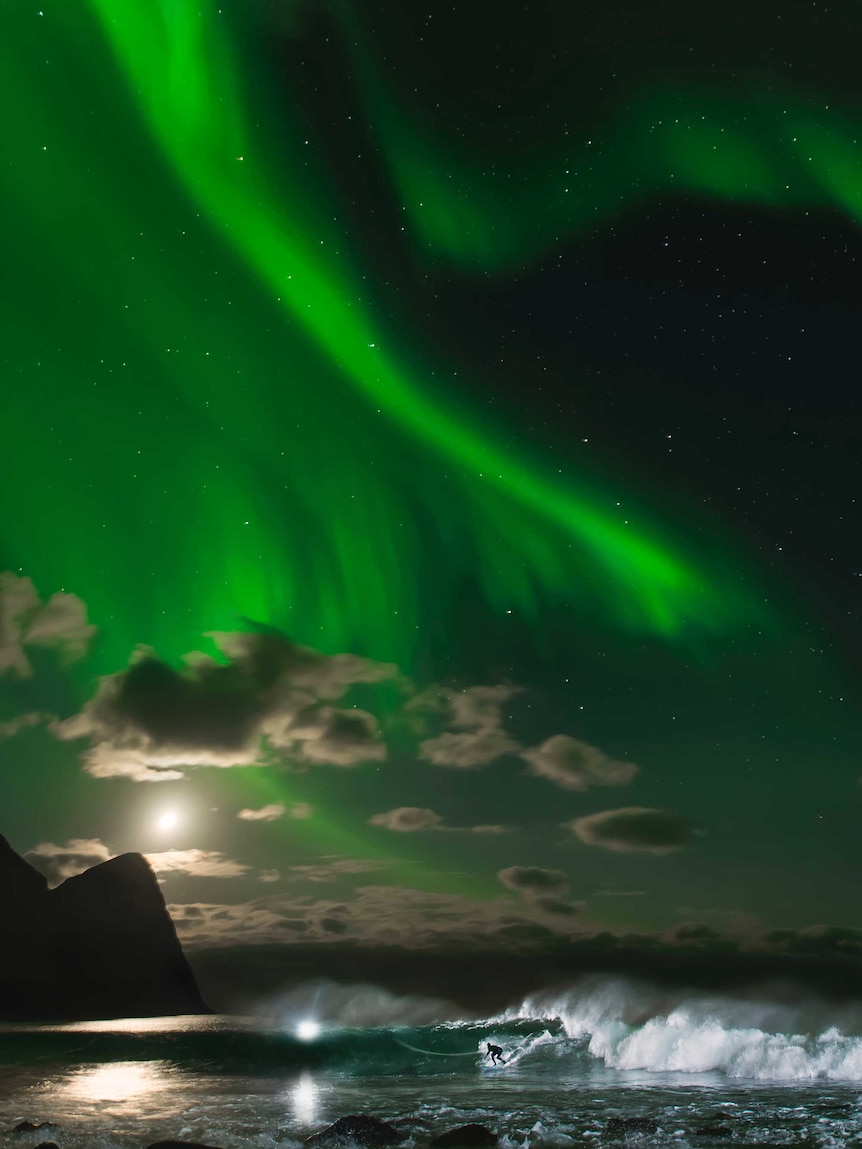 Mick Fanning surfs a wave under the Northern Lights in Norway.