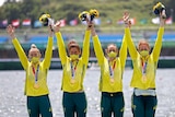 Four women wearing yellow jackets hold their arms in the air