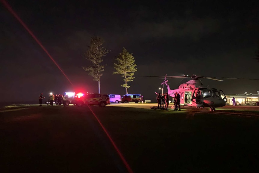 a helicopter and rescue vehicles on land at night