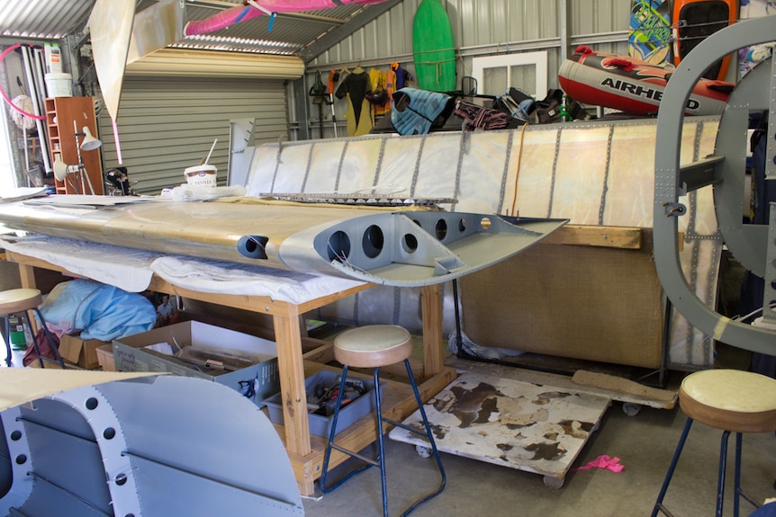 The wing of the Van's RV-12 plane lying on a workbench with the plane's tail piece suspended from the roof.