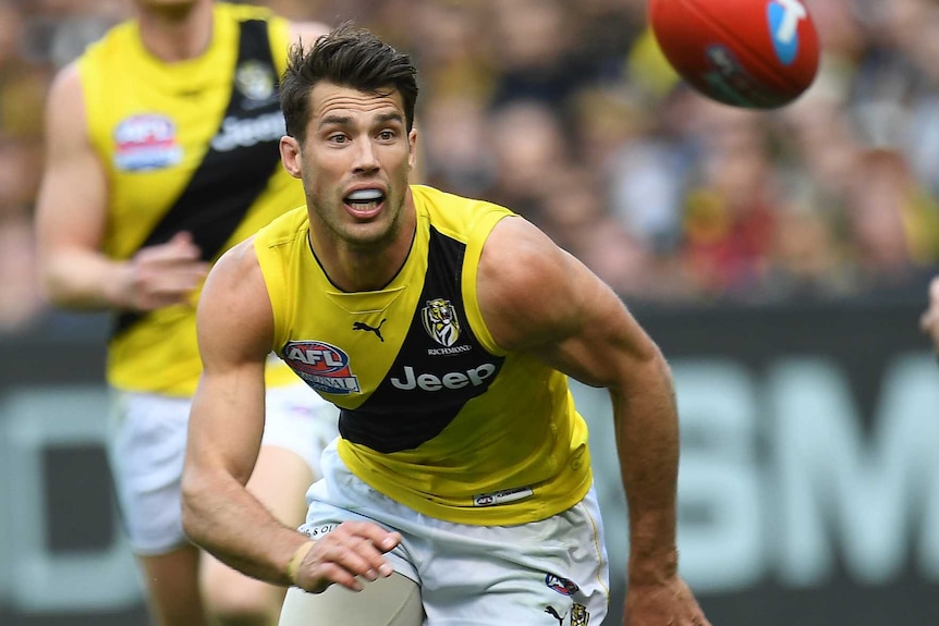 Alex Rance stares at the ball and prepares to move towards it.