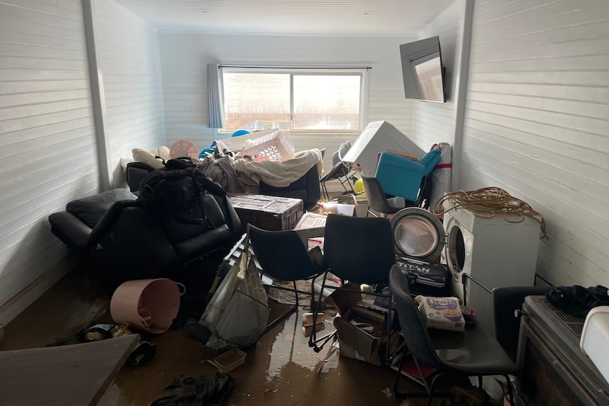 Jumble of belongings inside a room with water on the ground. 