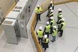 A birds eye view of a group of workers wearing high visibility clothing and hard hats.