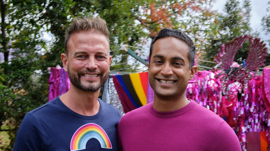Two men, Brad and Jeremy Fernandez smiling at the camera wearing bright clothing 