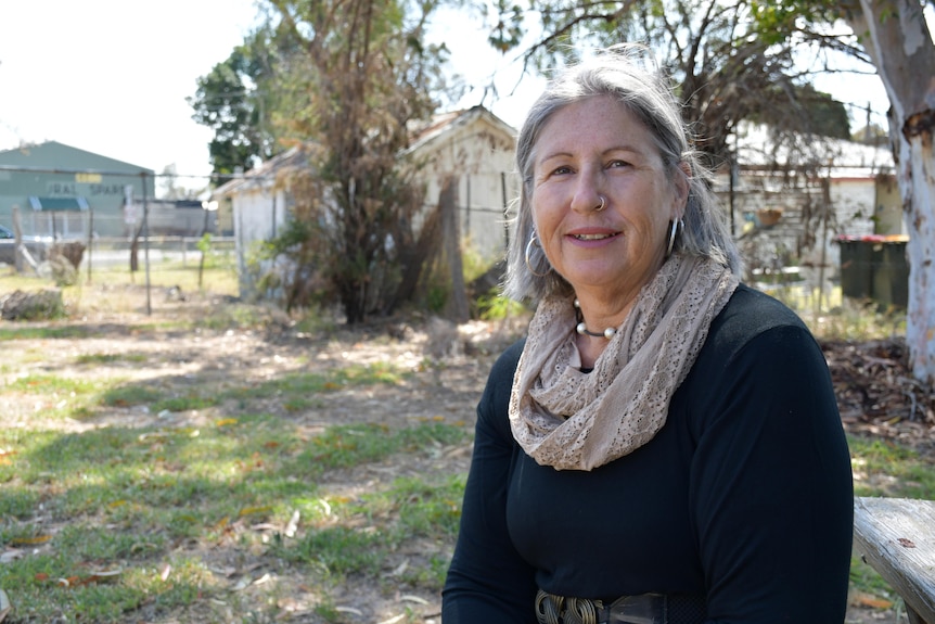 A woman with grey hair and a black dress smiles for the camera