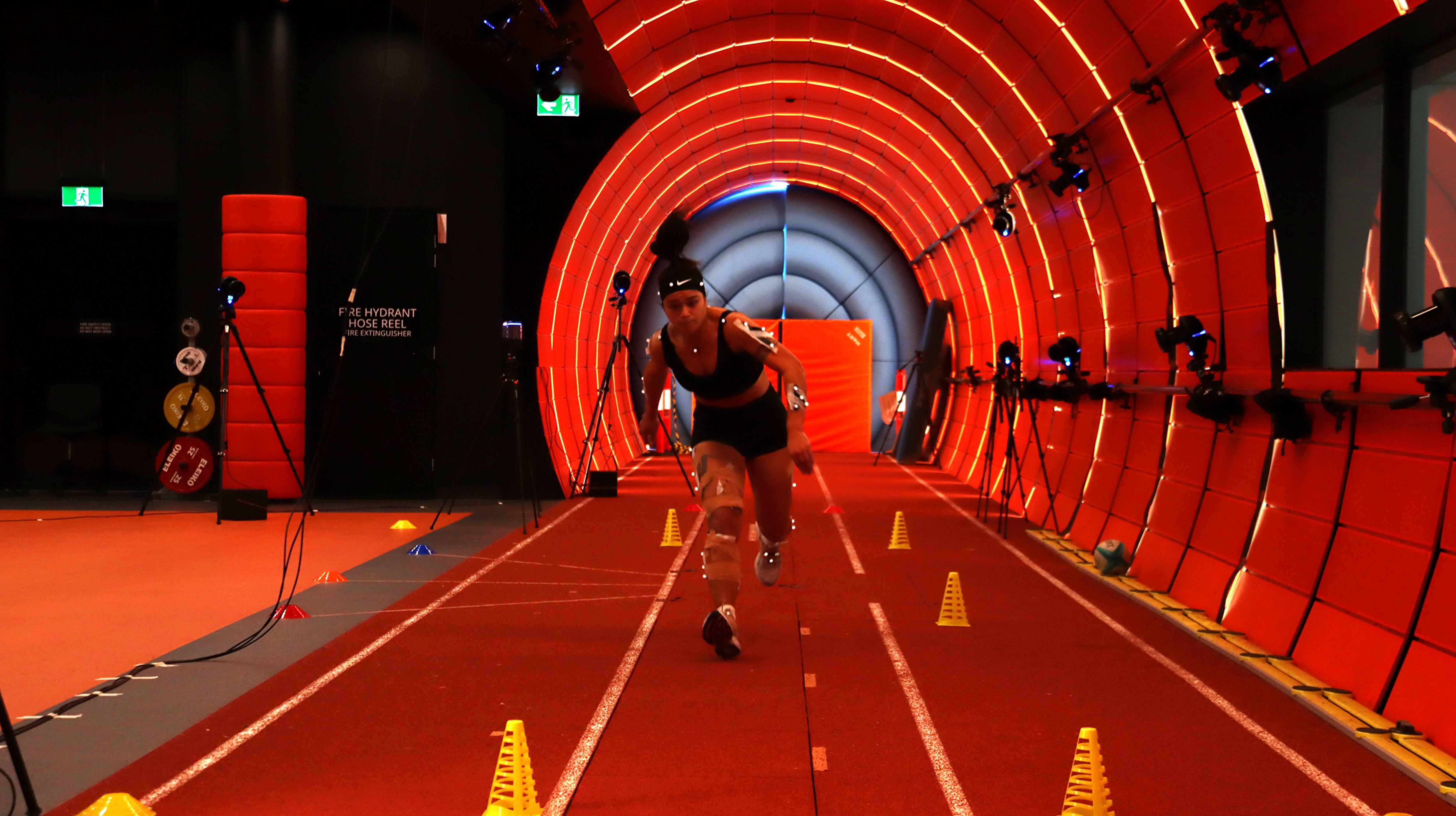Un jugador de rugby en una instalación de pruebas deportivas de color naranja se lanza hacia adelante.