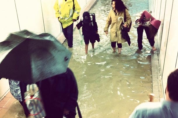 Commuters at Lewisham station in flooded pedestrian underpass.