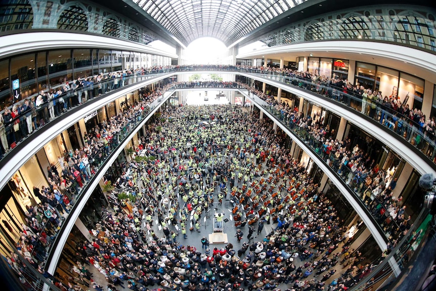 An elevated view of the Mall of Berlin, filled with musicians and spectators.