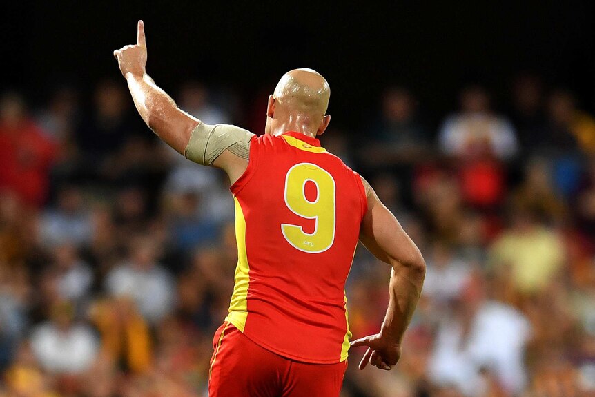 Gary Ablett from behind, raising his finger in the air in celebration