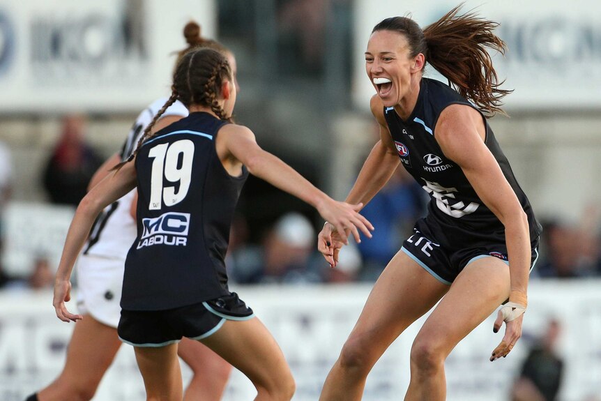 Alison Downie and Georgie Gee celebrate a goal for Carlton against Collingwood