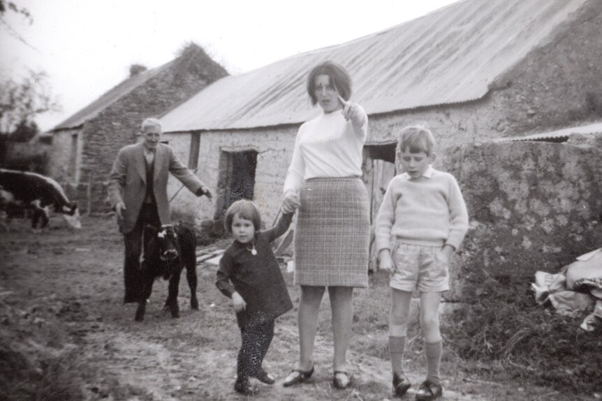 Black and white photo of Shane MacGowan as a child, with his mother Therese and sister Siobhan on the family farm in Ireland