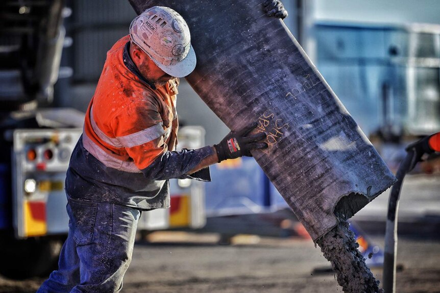 A worker pours concrete at a building construction site in Brisbane.
