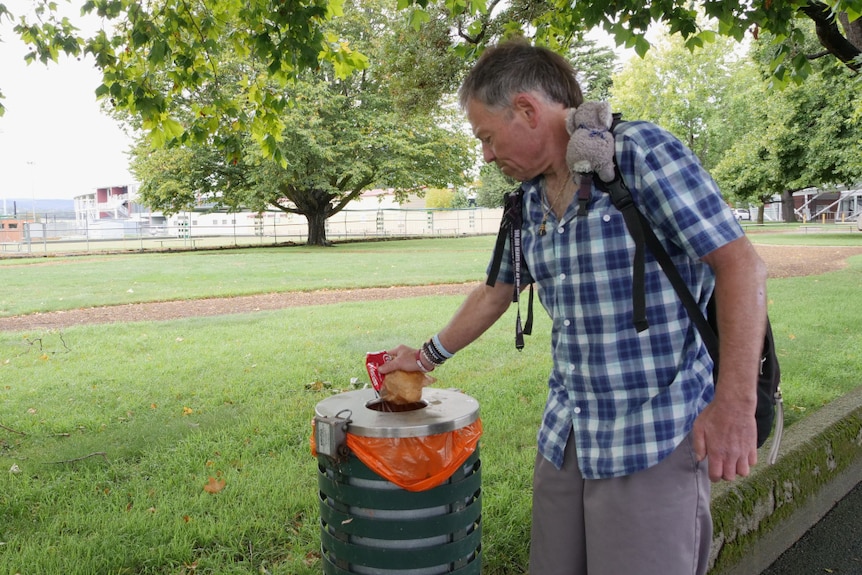 A man putting rubbish into a bin