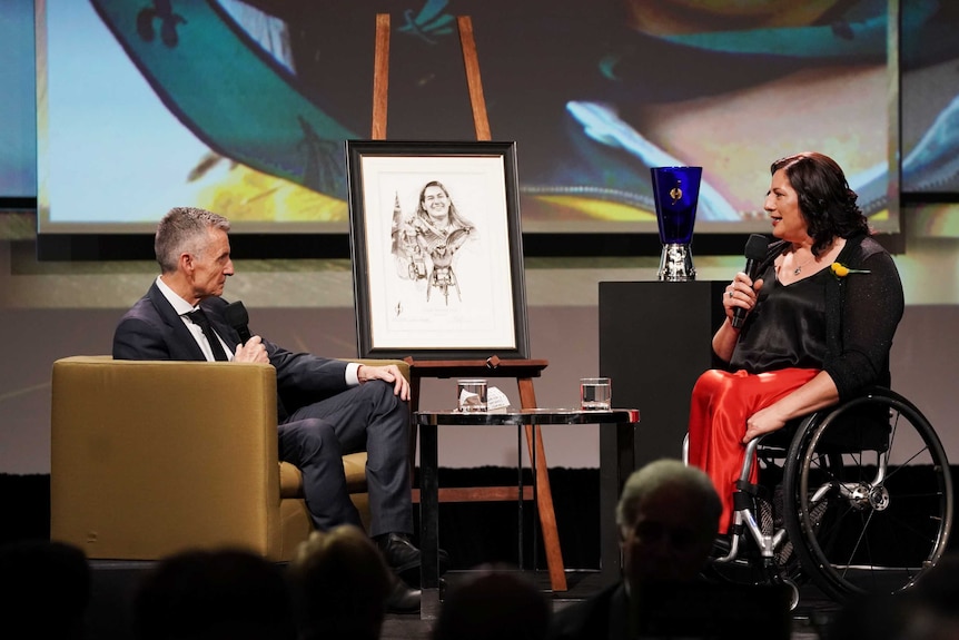 A woman in a wheelchair takes part in a Q & A after being honoured at a sports awards night.