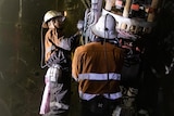 Two workers operate a large drill in an underground mine.