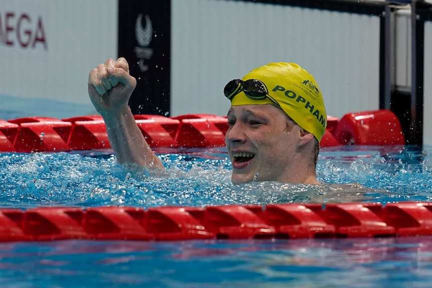 An Australian male swimmer pumps his right fist in the pool after winning tokyo Paralympic gold.