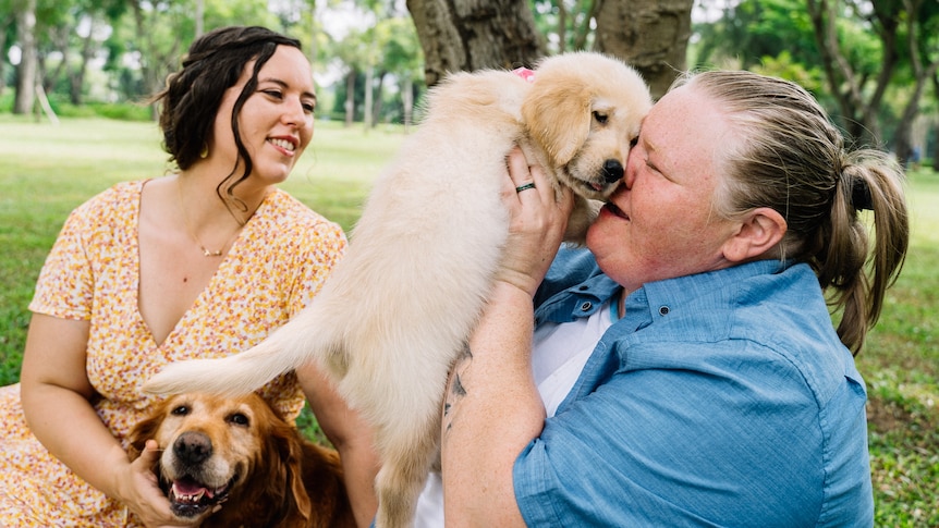 two women patting their dogs