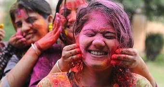 Indian girls play with colored powder during Holi festival