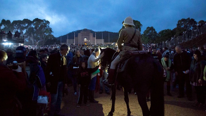 Crowds pat a horse after the Anzac Day dawn service at the Australian War Memorial in Canberra.
