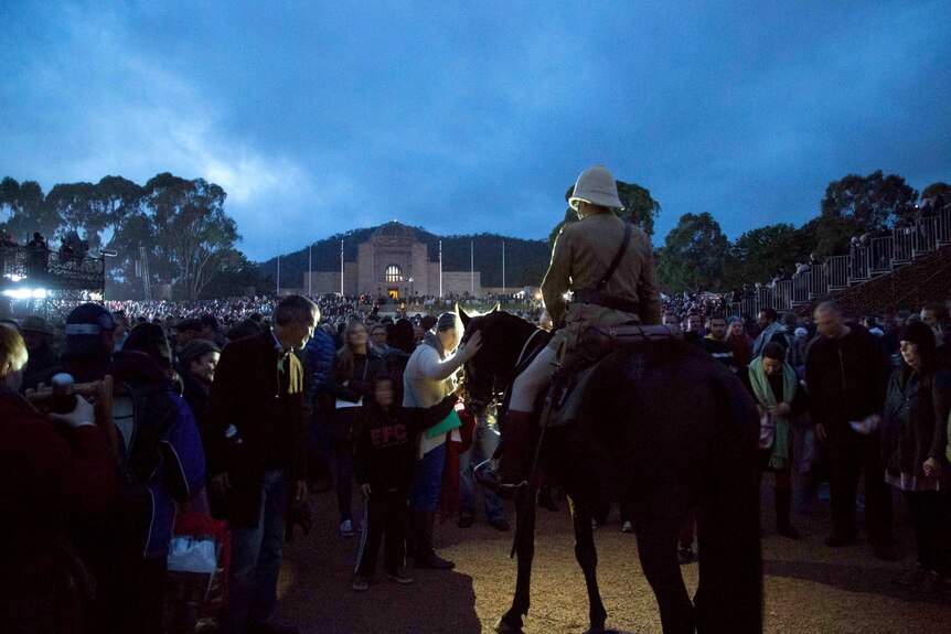 Crowds pat a horse after the Anzac Day dawn service at the Australian War Memorial in Canberra.