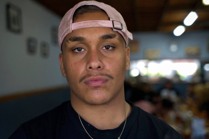 Boy with pink cap looking at camera.