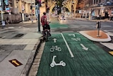 A separated bike lane through Brisbane CBD with an e-scooter stencil on the green paint