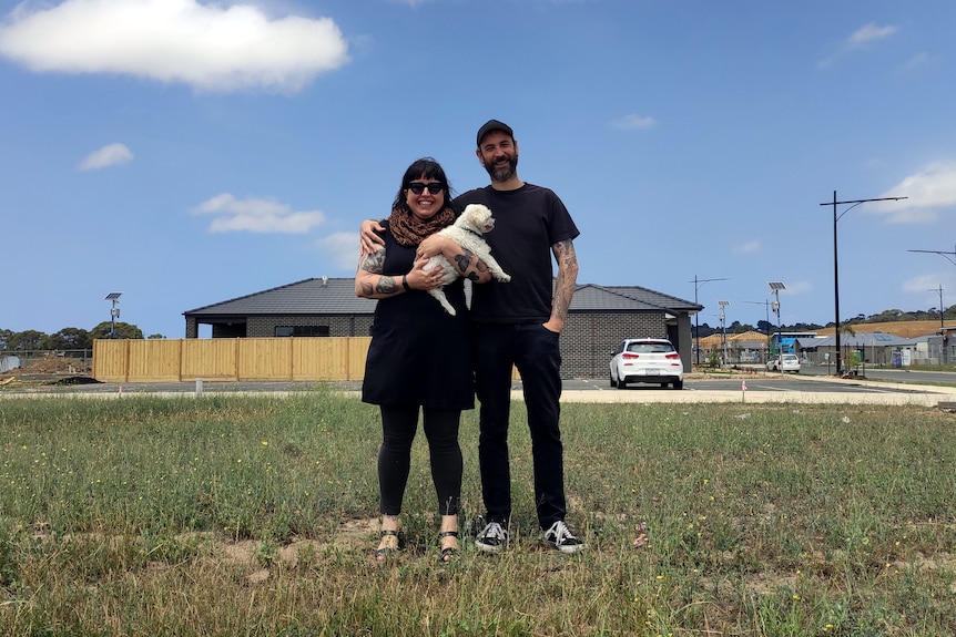 Carla Donnelly and her partner smile while standing on a block of land.