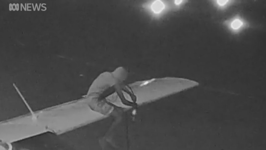 Person siphoning avgas from fuel tanks in the wings of a plane.