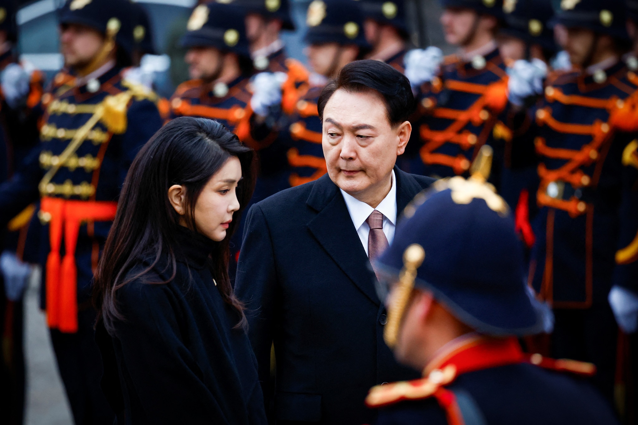 Yoon Suk Yeol and his wife Kim Keon Hee stand with a line of guards at a wreath laying ceremony.