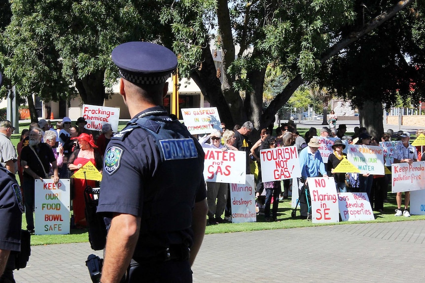 Protestors hold signs against fracking and unconventional gas mining