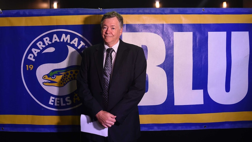 The administrator of the Parramatta Leagues Club standing in front of a club banner saying Blue and Gold.