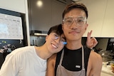 Jacky leans his head on on his boyfriend's shoulders as they stand together in the kitchen. 