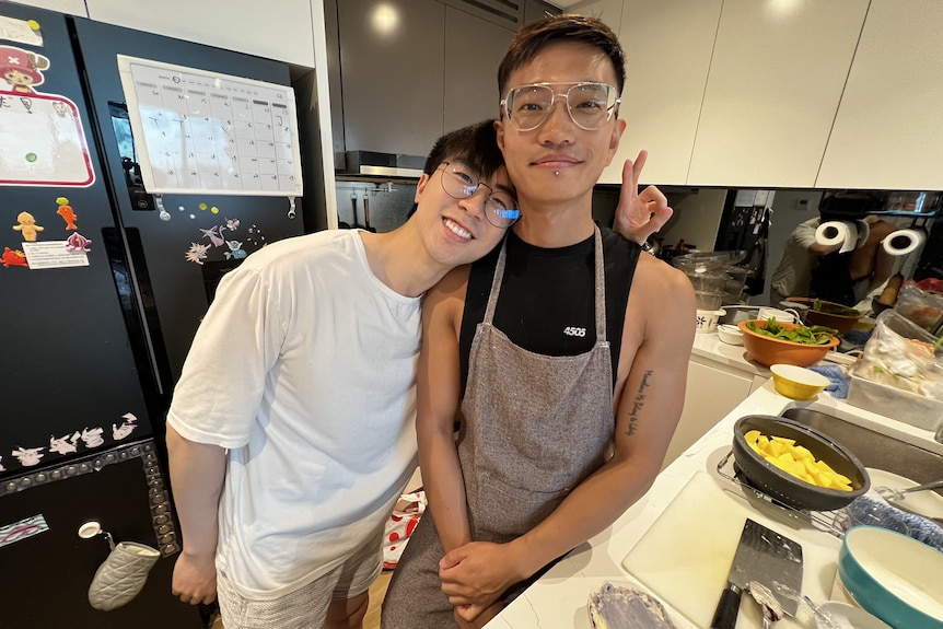 Jacky leans his head on on his boyfriend's shoulders as they stand together in the kitchen. 